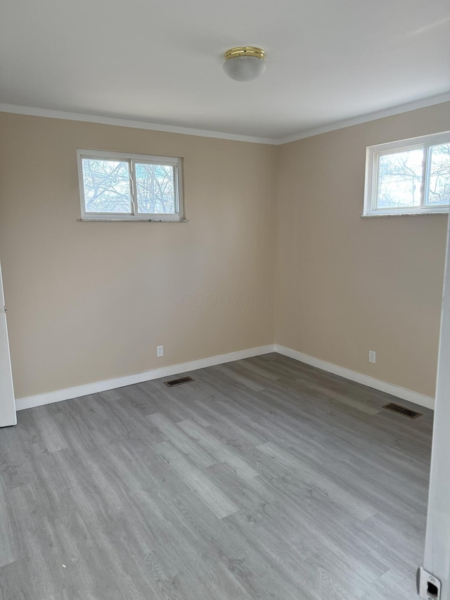 spare room with ornamental molding, wood finished floors, visible vents, and baseboards