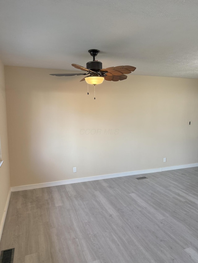 empty room featuring wood finished floors, visible vents, and baseboards