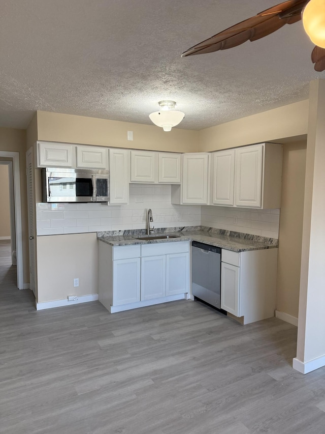 kitchen with stainless steel appliances, backsplash, light wood-type flooring, and a sink