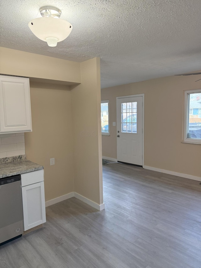 kitchen featuring light wood-type flooring, a wealth of natural light, white cabinetry, and dishwasher