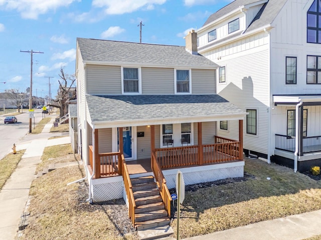 view of front of house featuring a shingled roof, a chimney, stairway, covered porch, and board and batten siding