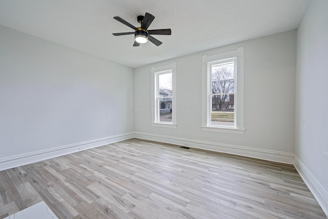 unfurnished room with light wood finished floors, visible vents, ceiling fan, a textured ceiling, and baseboards