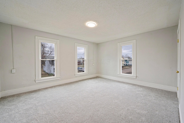 carpeted empty room featuring a textured ceiling and baseboards