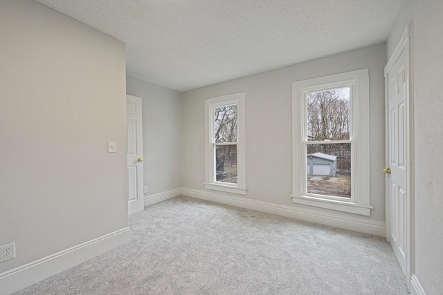 carpeted empty room with baseboards and a textured ceiling