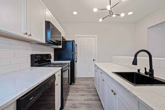 kitchen featuring black appliances, light stone counters, a sink, and white cabinets