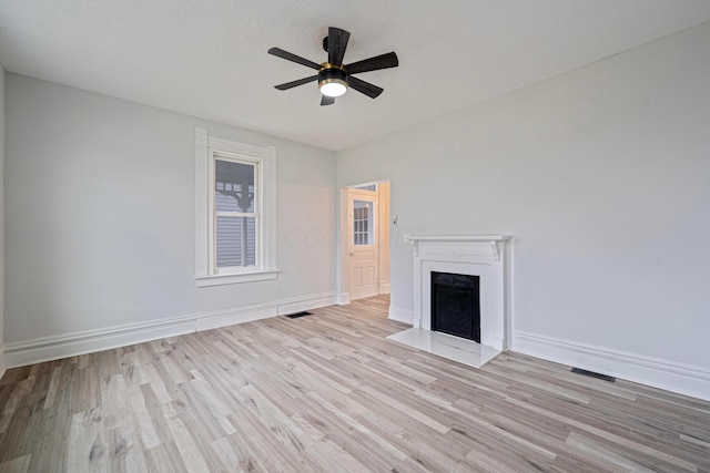 unfurnished living room with a fireplace with flush hearth, ceiling fan, baseboards, and wood finished floors