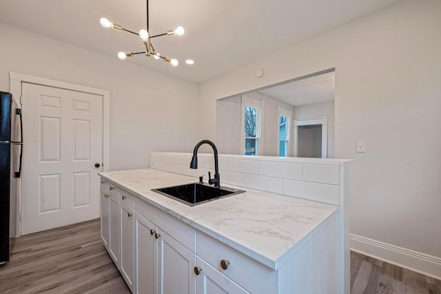 kitchen with light wood-type flooring, a kitchen island, white cabinetry, and a sink