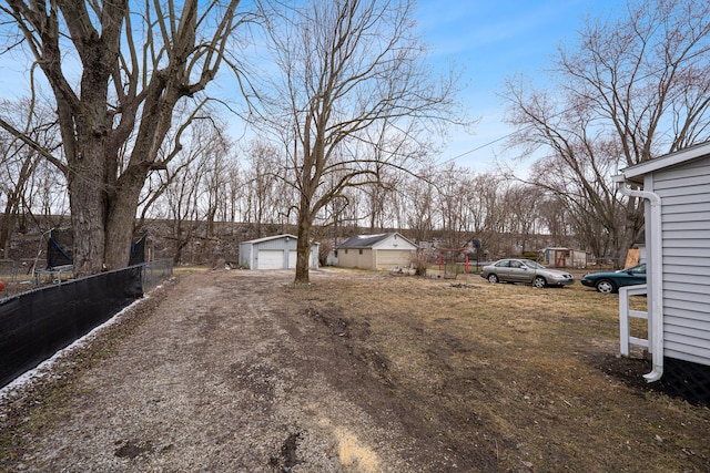 view of yard with a garage, an outbuilding, fence, and driveway