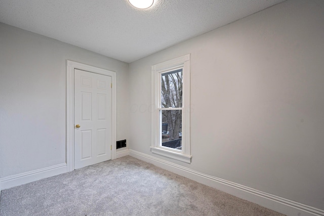 spare room featuring carpet, baseboards, and a textured ceiling