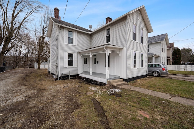 view of front of home with covered porch, a chimney, and fence