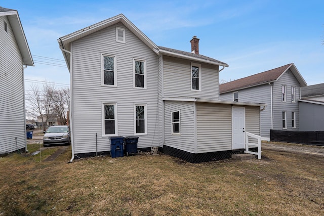 rear view of property with a chimney and a lawn