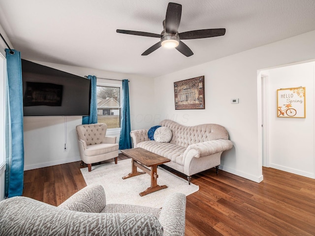 living room with a ceiling fan, baseboards, and wood finished floors