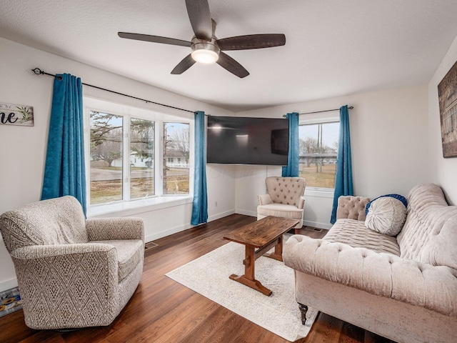 living area featuring visible vents, ceiling fan, baseboards, and wood finished floors