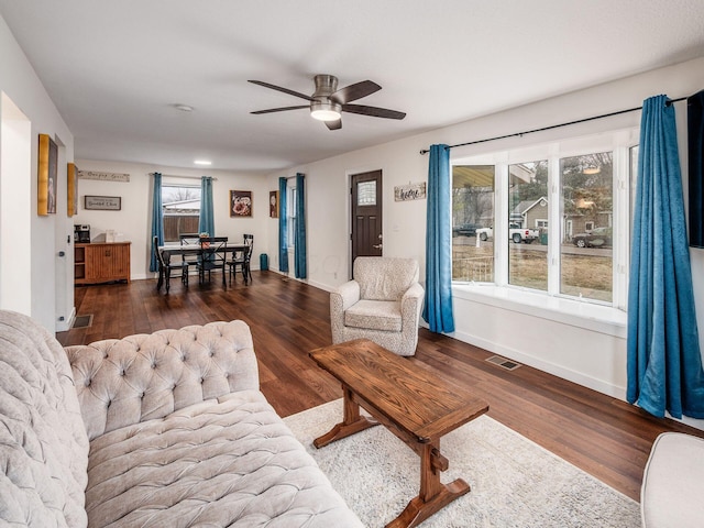 living area with visible vents, ceiling fan, baseboards, and wood finished floors