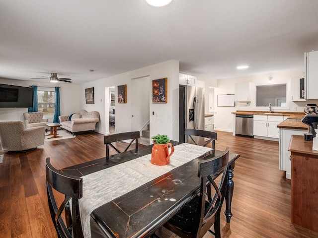 dining space featuring baseboards, ceiling fan, stairway, and dark wood-style flooring