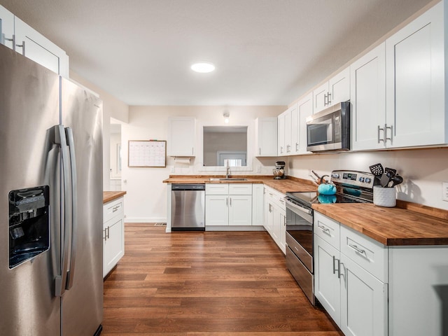 kitchen featuring appliances with stainless steel finishes, dark wood finished floors, butcher block counters, and a sink