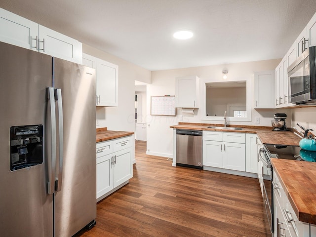 kitchen featuring dark wood-type flooring, wood counters, stainless steel appliances, and a sink