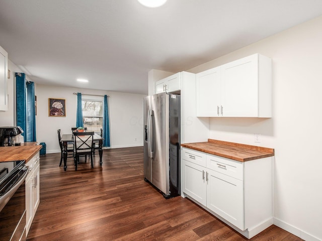 kitchen featuring dark wood-type flooring, wood counters, white cabinetry, baseboards, and appliances with stainless steel finishes