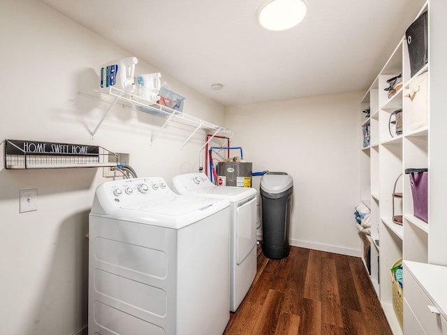 clothes washing area featuring electric water heater, laundry area, baseboards, dark wood-style floors, and washer and clothes dryer