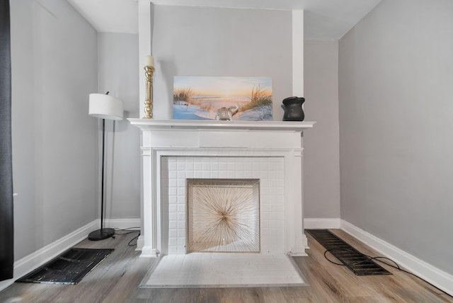 interior details featuring a fireplace, wood finished floors, visible vents, and baseboards