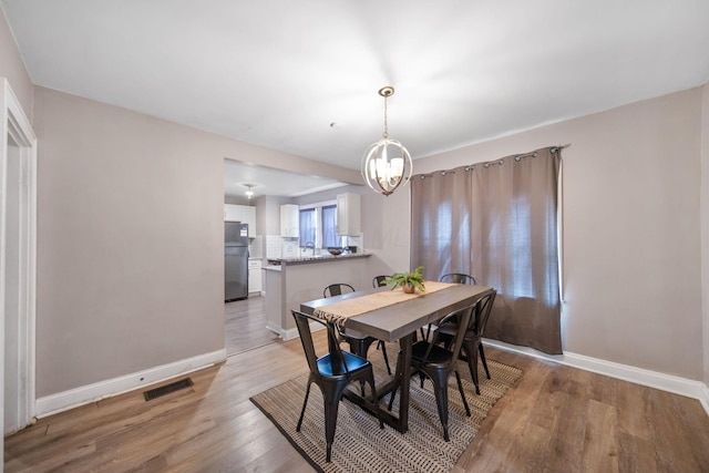 dining space with an inviting chandelier, light wood-style flooring, and baseboards
