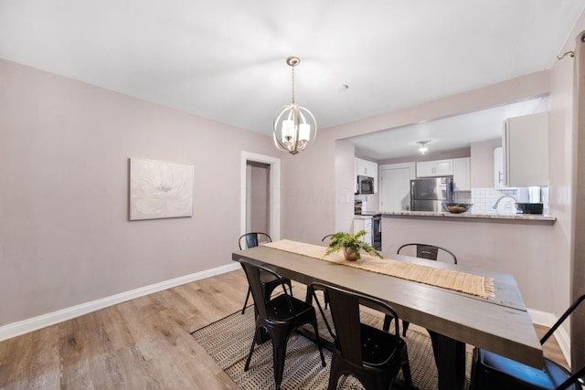 dining area featuring a notable chandelier, light wood-type flooring, and baseboards
