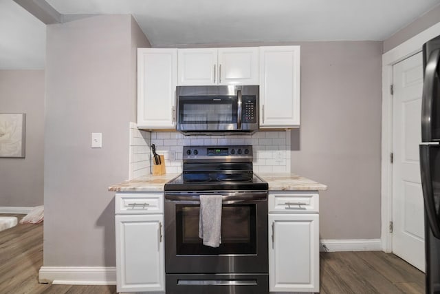 kitchen featuring dark wood-type flooring, backsplash, stainless steel microwave, and electric range