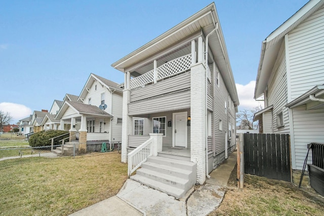 view of front of house featuring a front yard, fence, and a balcony