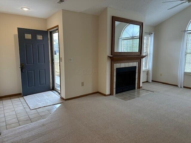 foyer entrance with light carpet, a fireplace, and baseboards