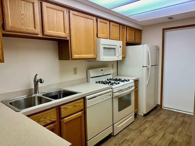 kitchen featuring white appliances, visible vents, light countertops, light wood-style floors, and a sink