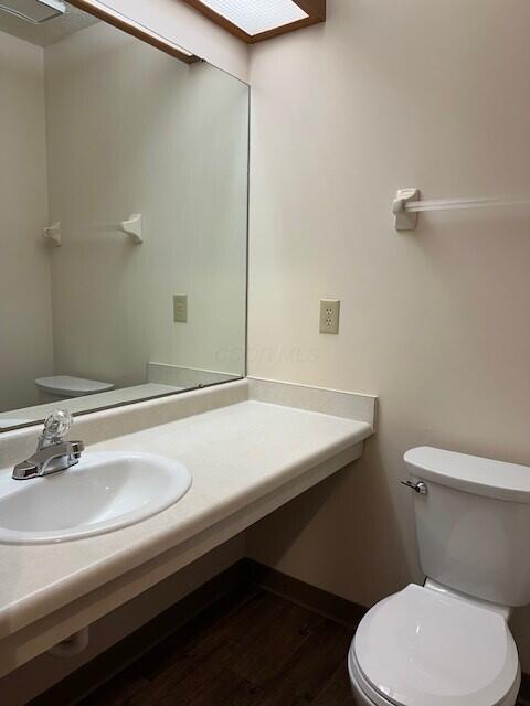 bathroom featuring toilet, wood finished floors, and vanity