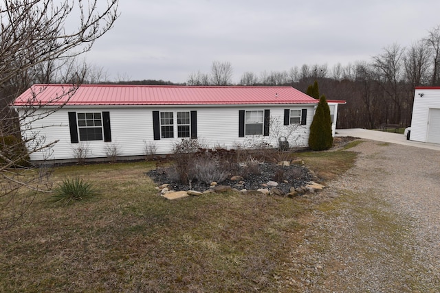 view of front of property featuring driveway, a front lawn, and metal roof