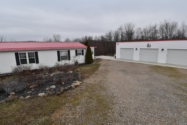 view of front of home with a garage, metal roof, and an outdoor structure