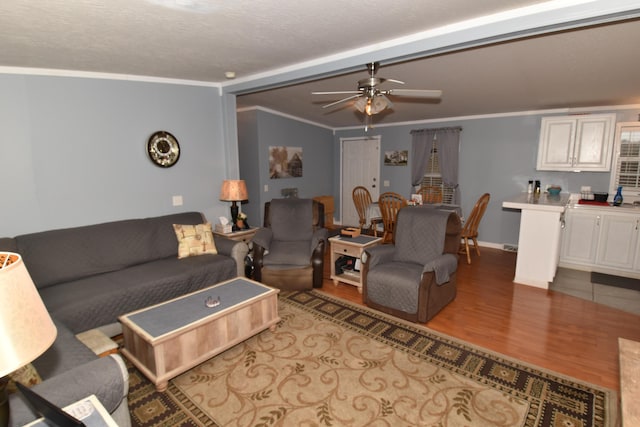 living area with a ceiling fan, crown molding, and wood finished floors