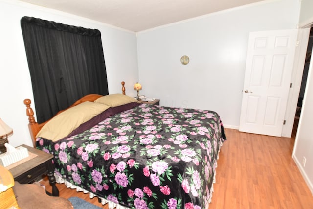 bedroom featuring baseboards, ornamental molding, and wood finished floors