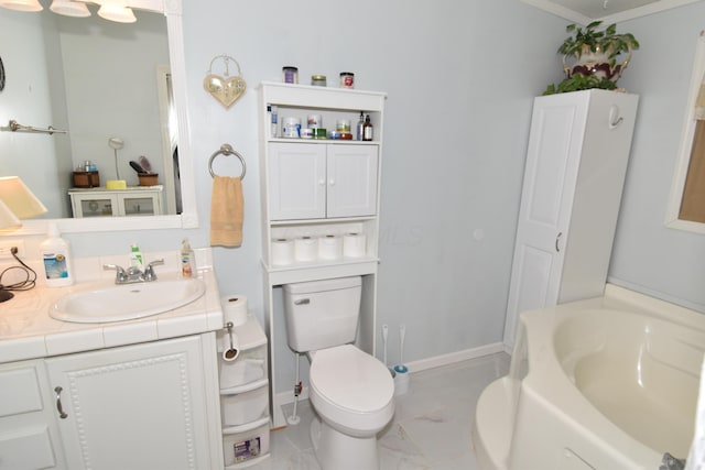 bathroom with marble finish floor, a garden tub, toilet, vanity, and baseboards