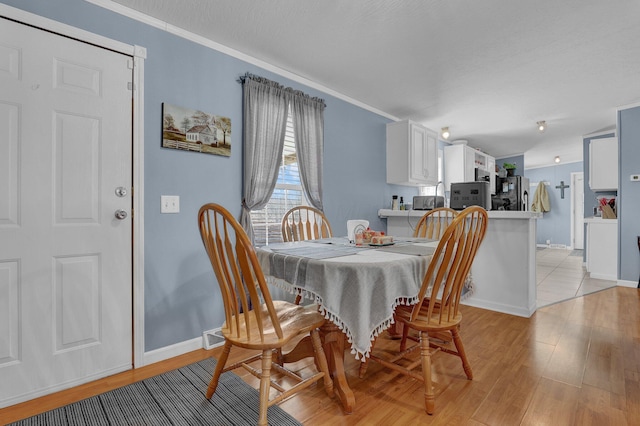 dining area with baseboards, light wood-style flooring, and ornamental molding