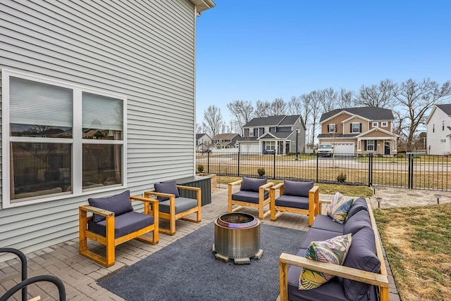 view of patio / terrace with an outdoor living space with a fire pit, fence, and a residential view