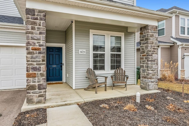 view of exterior entry featuring a porch, a garage, and stone siding