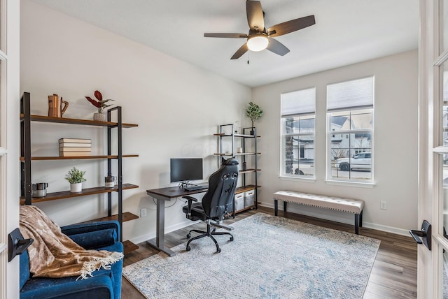 office space featuring a ceiling fan, baseboards, and wood finished floors