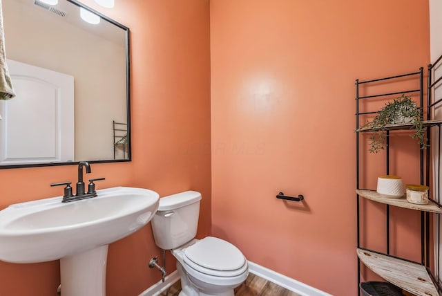 bathroom featuring wood finished floors, baseboards, visible vents, a sink, and toilet