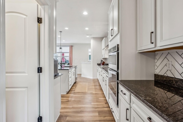 kitchen with decorative backsplash, recessed lighting, light wood-style floors, white cabinets, and a sink