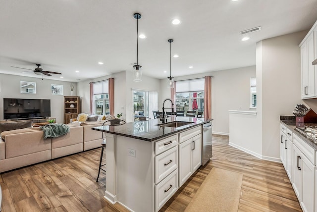 kitchen with visible vents, a sink, light wood-style floors, a breakfast bar area, and dishwasher