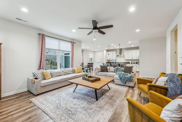 living area featuring a ceiling fan, recessed lighting, visible vents, and light wood finished floors