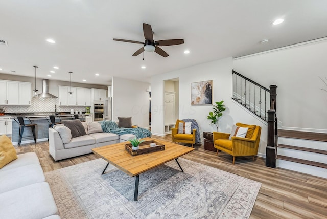 living area with recessed lighting, ceiling fan, stairs, and light wood finished floors