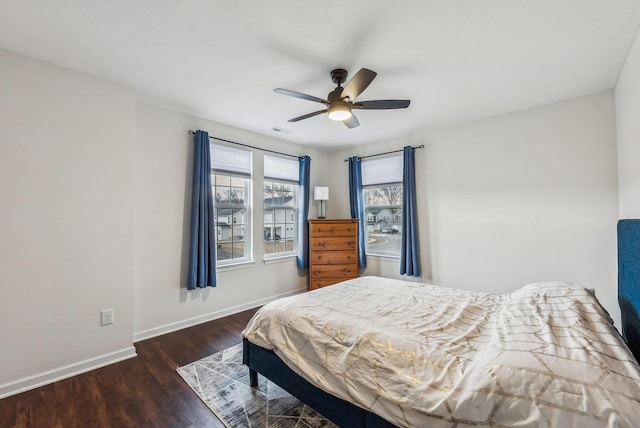 bedroom featuring a ceiling fan, visible vents, wood finished floors, and baseboards