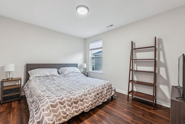 bedroom with wood finished floors, visible vents, and baseboards