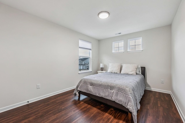 bedroom with wood finished floors, visible vents, and baseboards