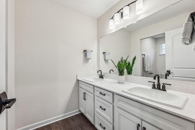 full bath with a sink, baseboards, wood finished floors, and double vanity