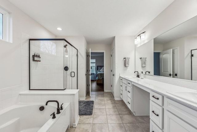 bathroom featuring a garden tub, double vanity, a stall shower, ensuite bath, and a sink